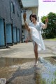 A woman in a white dress is standing in a puddle.