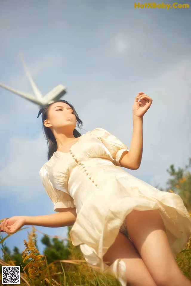 A woman in a white dress standing in a field.