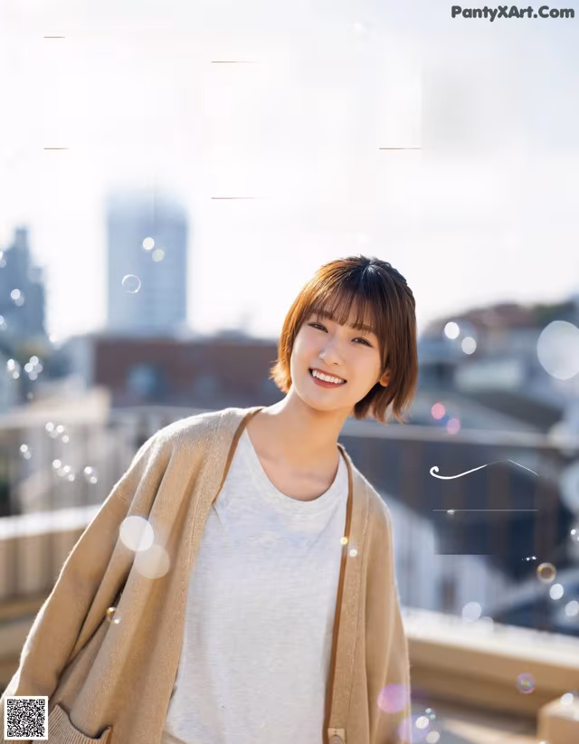 A woman in a white shirt and a beige cardigan smiles at the camera.