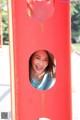 A woman is smiling through a hole in a red gate.