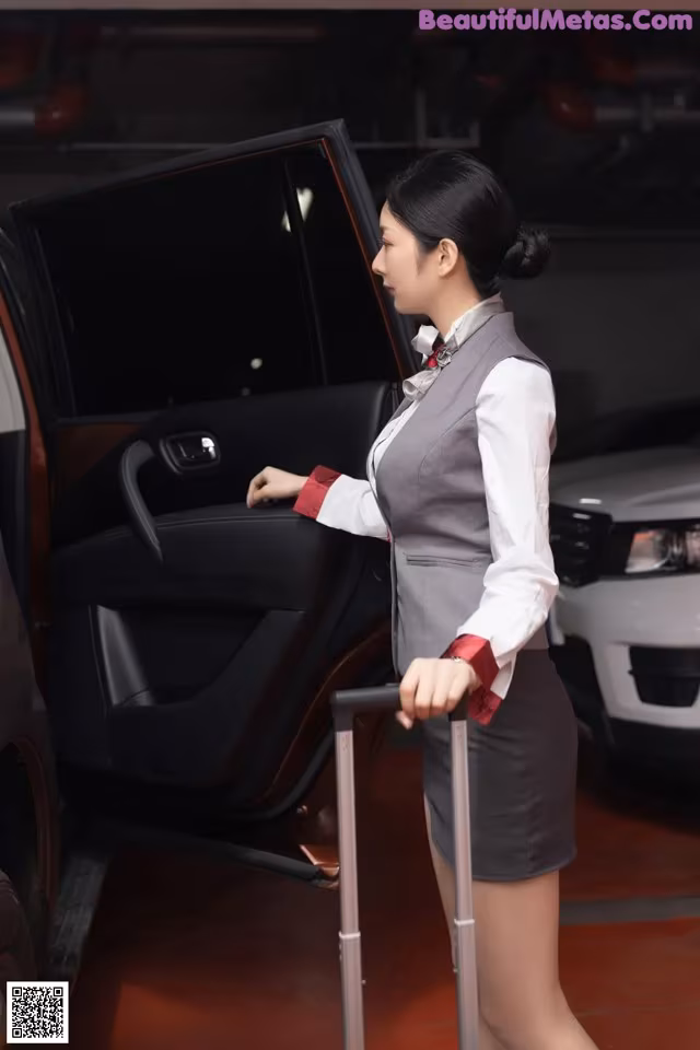 A woman standing next to a car with a cane.