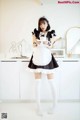 A woman in a maid outfit holding a cup of coffee.