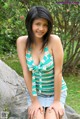 A young woman sitting on a rock in a park.