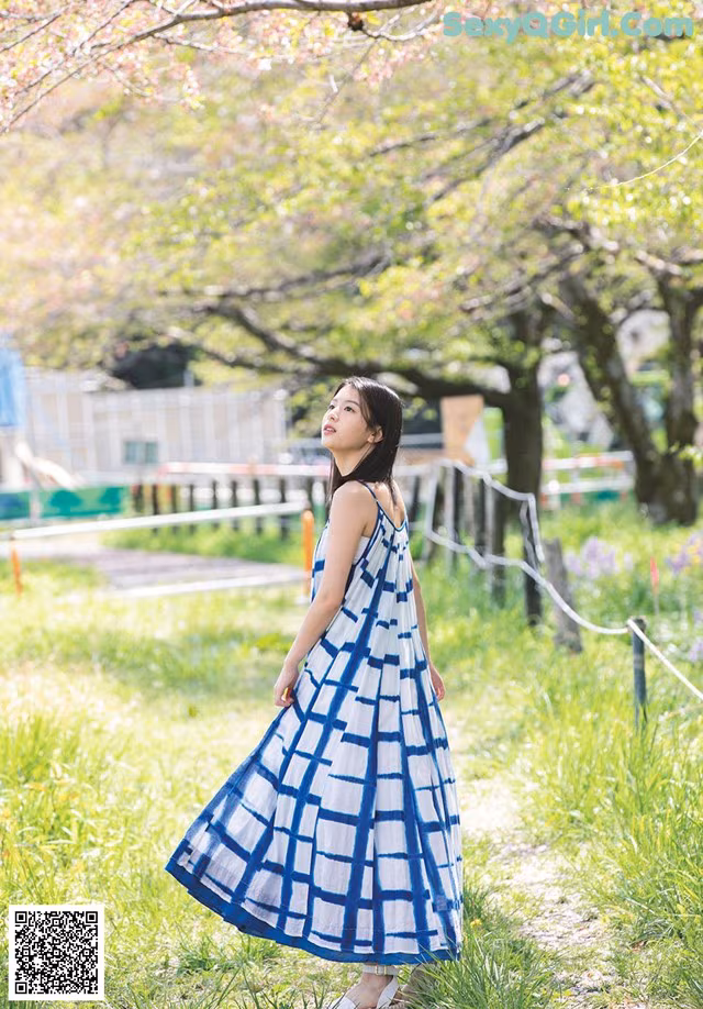 A woman in a blue and white dress standing in a field.