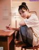 A woman sitting at a desk writing on a piece of paper.