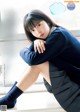 A woman in a school uniform sitting on a window sill.