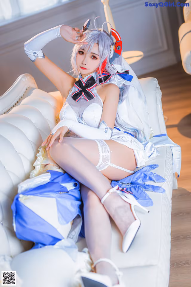 A woman in a white and blue outfit sitting on a white couch.