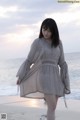 A woman standing on a beach next to the ocean.