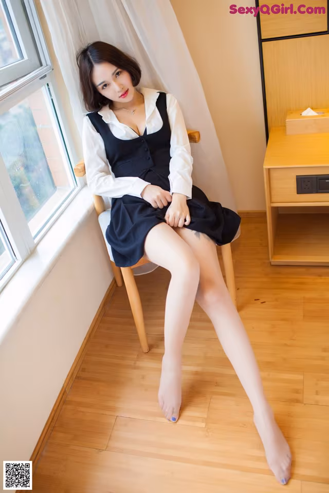 A woman sitting on a chair in front of a window.