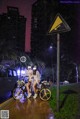 A couple of people riding bikes down a street at night.