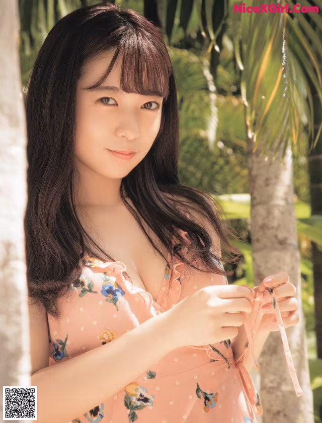 A woman in a pink dress standing next to a palm tree.