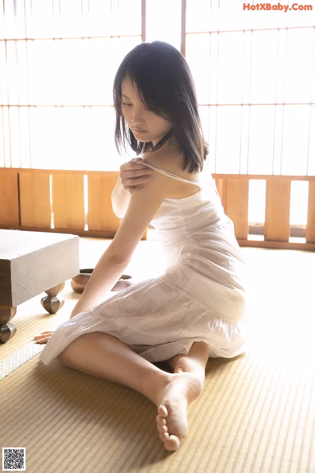A woman in a white dress sitting on the floor.