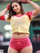 A woman in a baseball uniform holding a baseball glove.