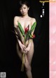 A naked woman holding a bunch of flowers in her hands.