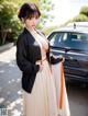 A woman in a black and white kimono standing next to a car.