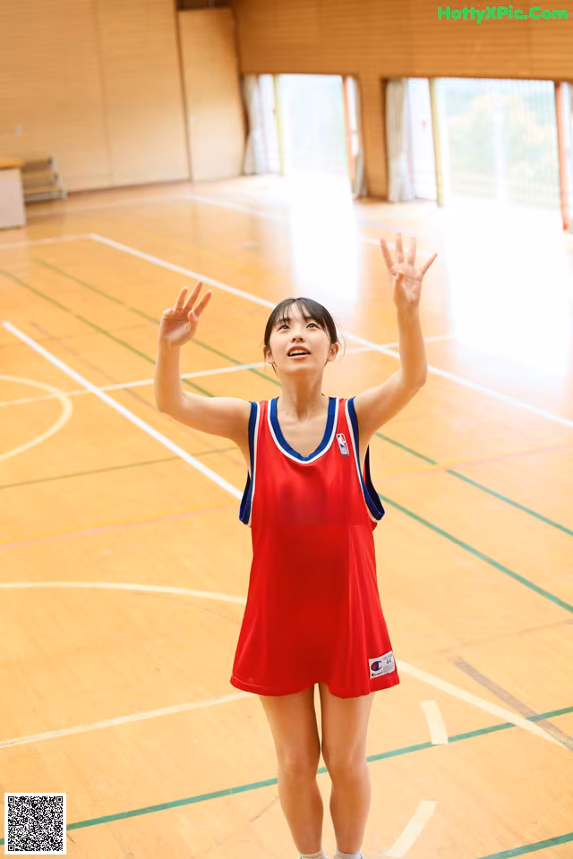 A woman in a red and blue uniform standing on a basketball court.