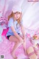 A young woman sitting on a pink rug with stuffed animals.