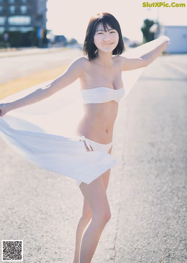 A woman in a white bikini standing on a road.