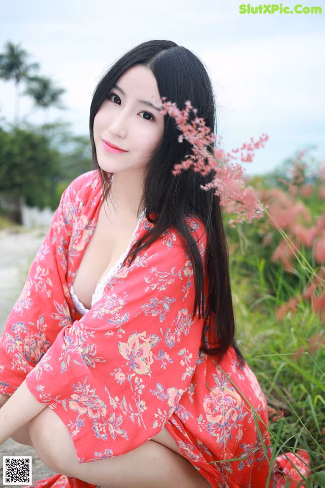 A woman in a red kimono sitting on the ground.