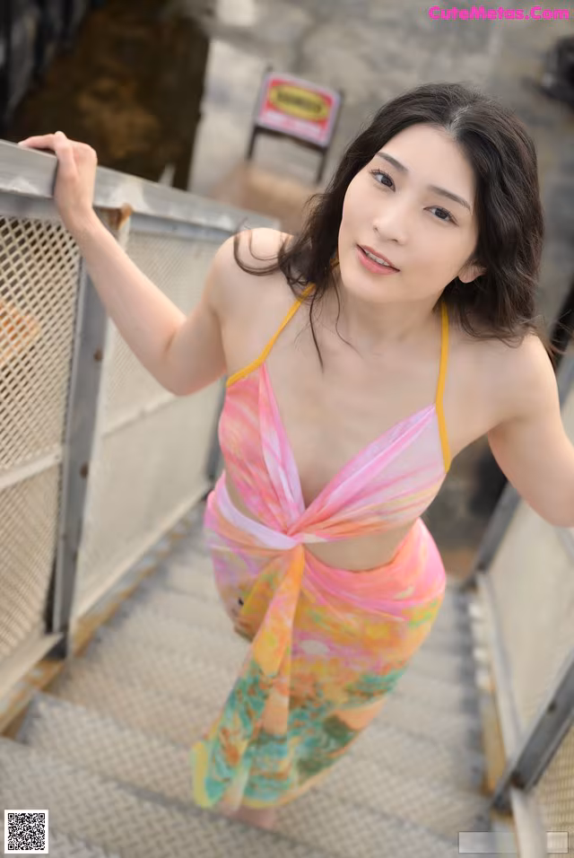 A woman in a colorful dress standing on a set of stairs.